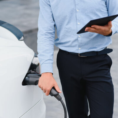 a businessman charges an electric car